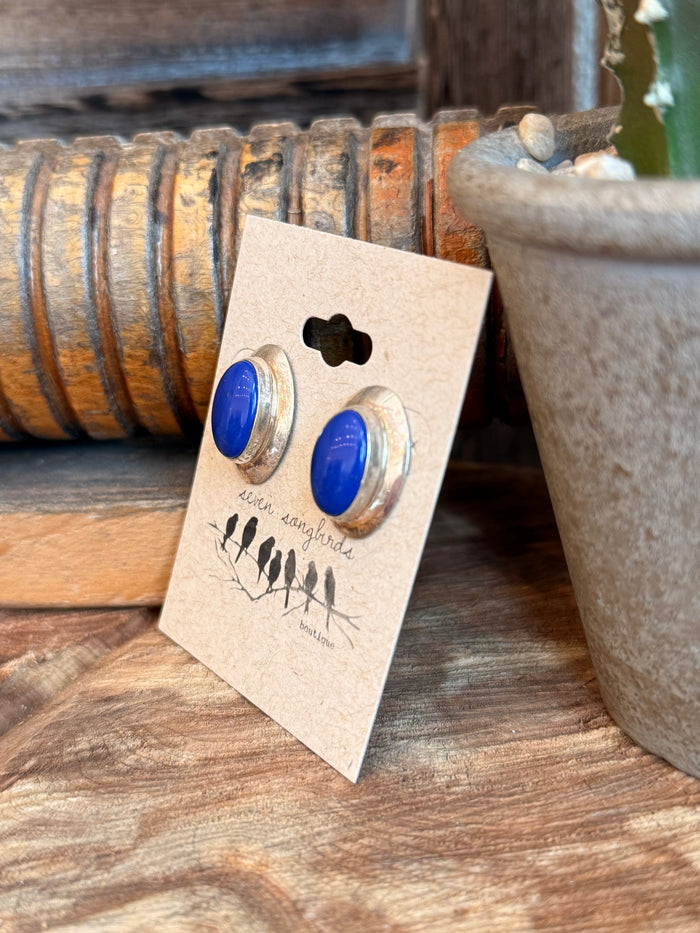 Blue oval lapis stud earrings with gold-tone settings, displayed on beige card
