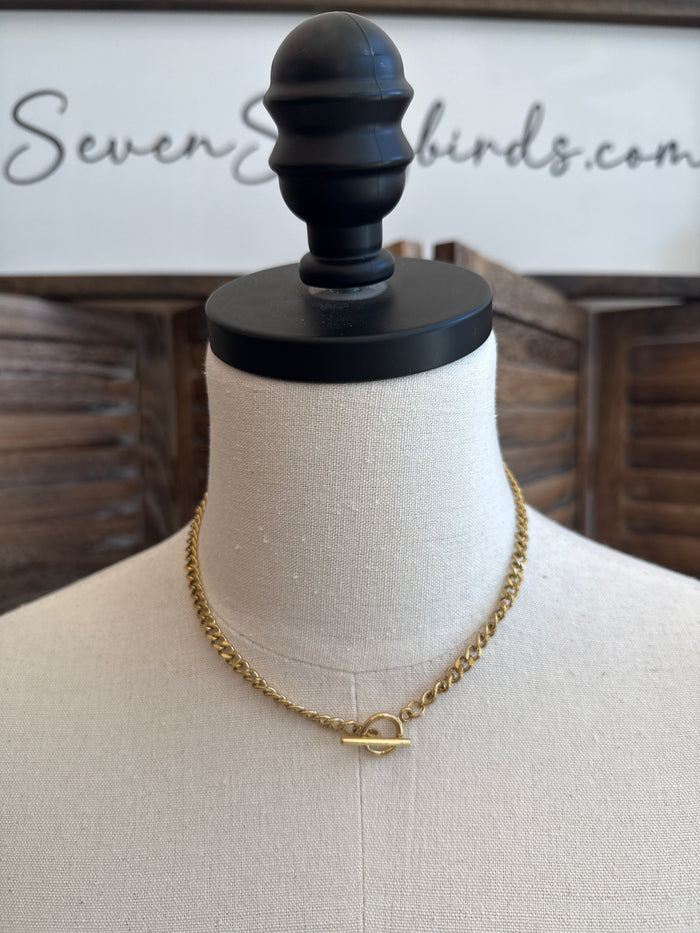 Gold-tone toggle clasp necklace with oval ring and bar hardware at center