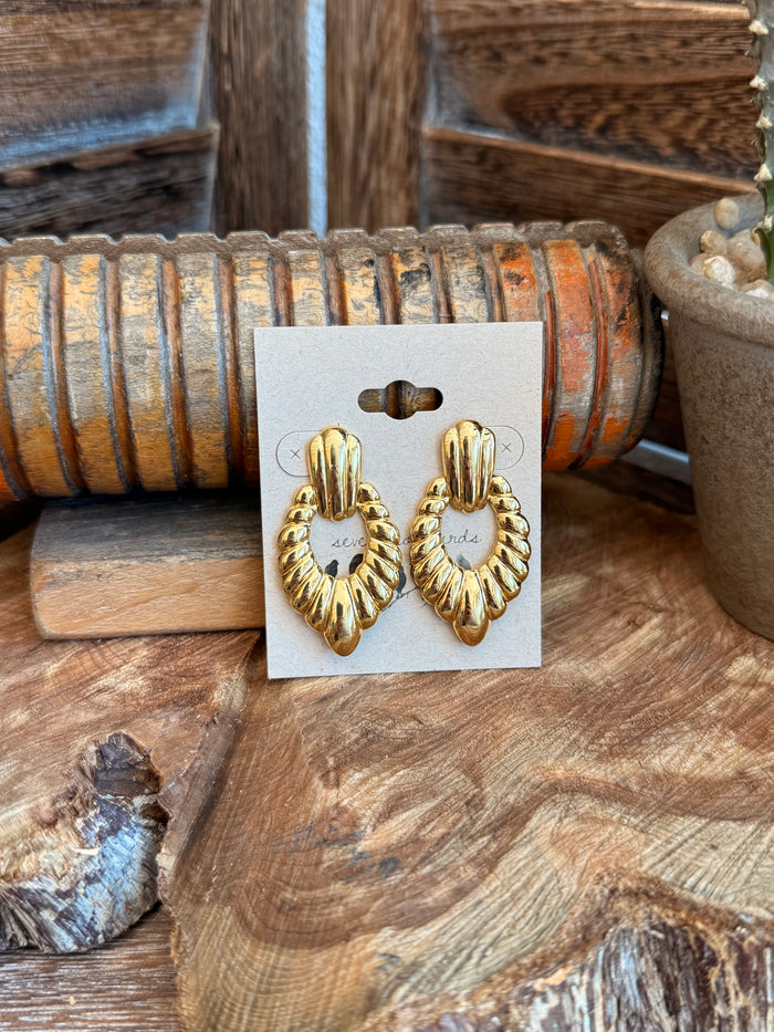 Gold textured teardrop stud earrings with ribbed detail, on display card