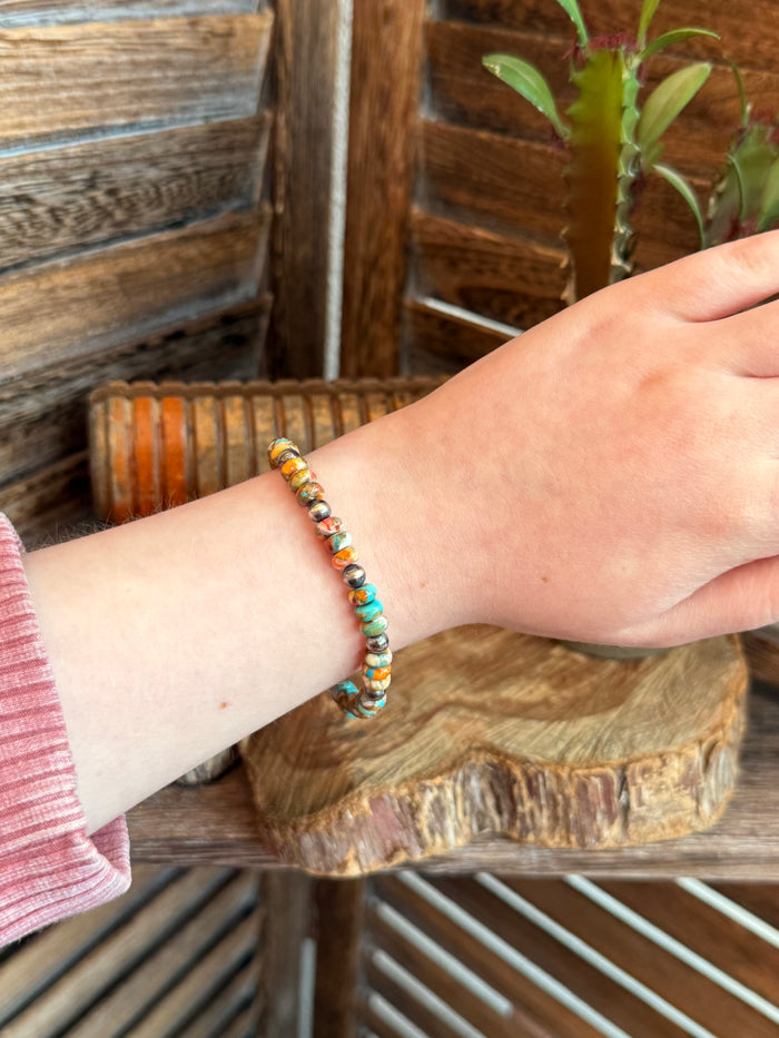 Turquoise and orange bead stretch bracelet on wrist, silver pearl accents