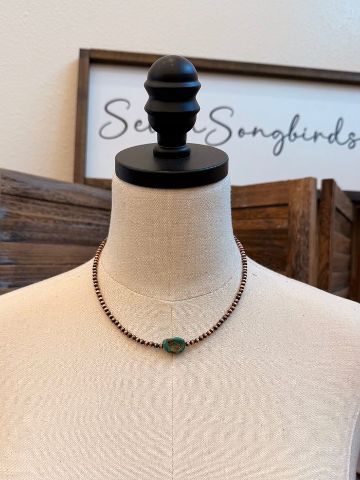 Turquoise copper beaded necklace with central oval turquoise stone on mannequin