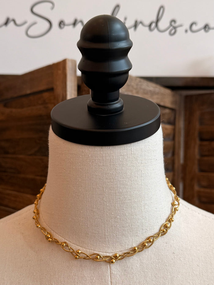 Gold-plated woven chain necklace on mannequin, link-and-ring pattern