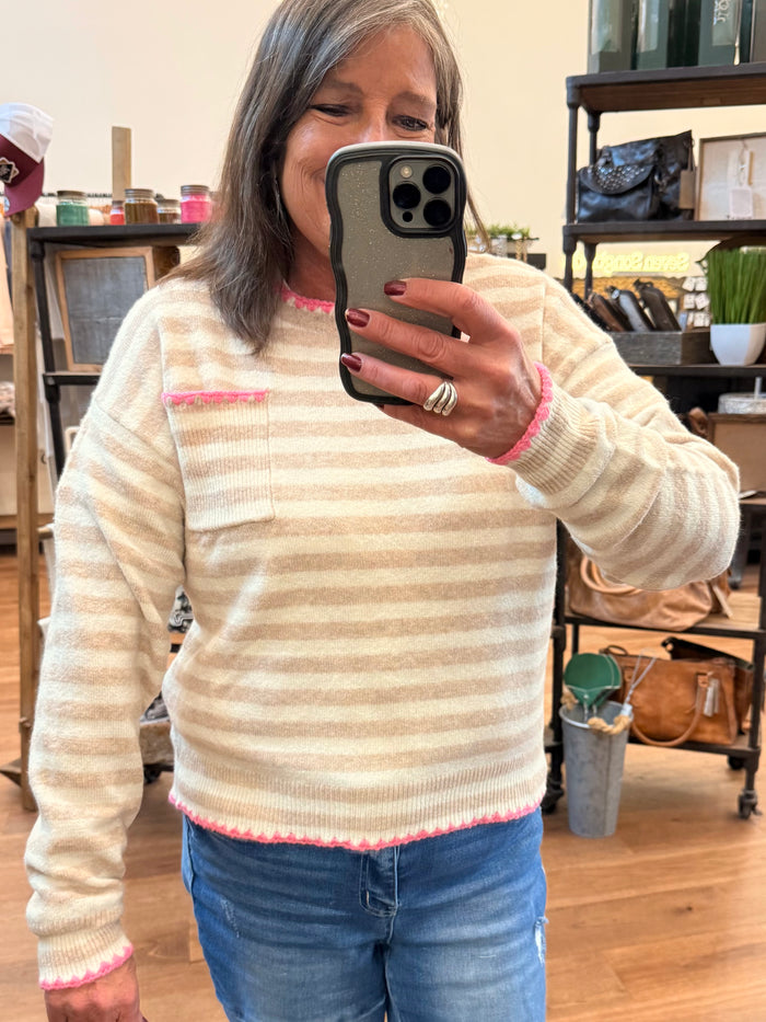 Cream crew neck sweater with pink striped bands and whip-stitched collar, cuffs, and hem