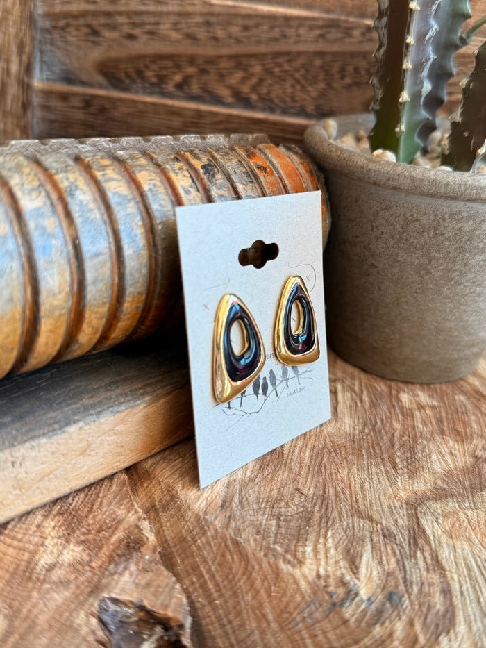Gold-tone stud earrings with dark blue teardrop stones on display card