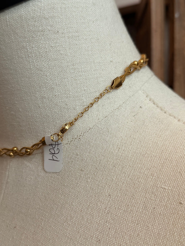 Gold-plated chain necklace with small charm tag showing 'be'