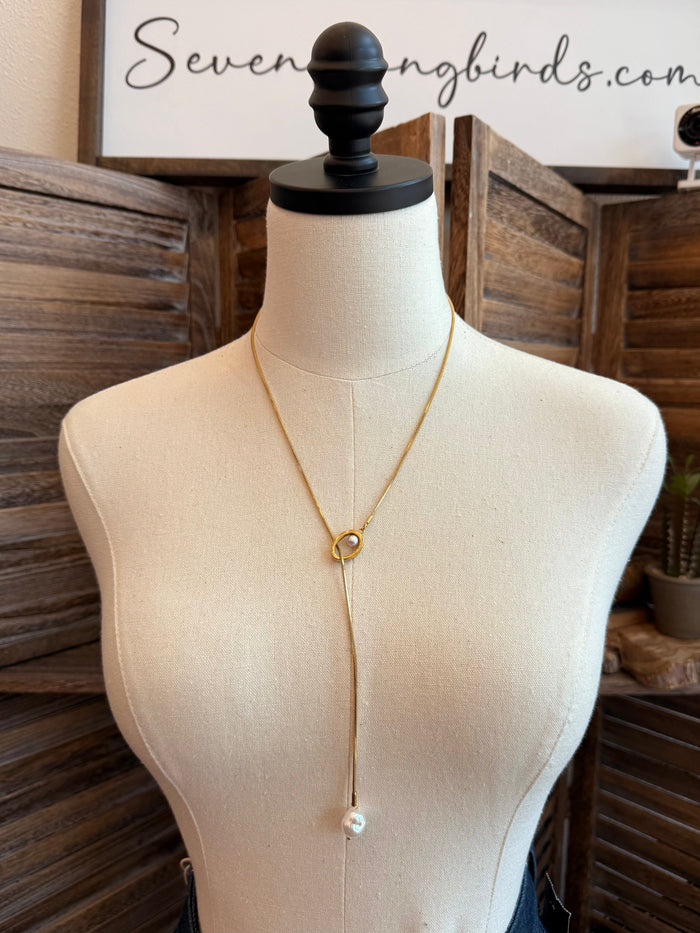 Gold lariat pull-through necklace with pearl drop and circular clasp on mannequin