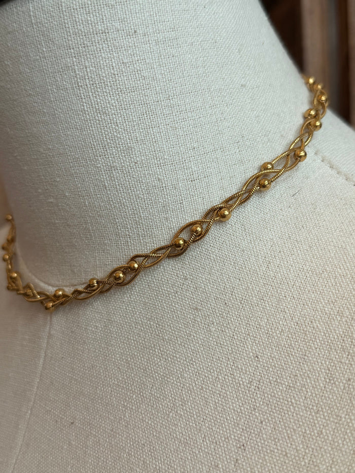 Gold-plated woven chain necklace detail with twisted oval links