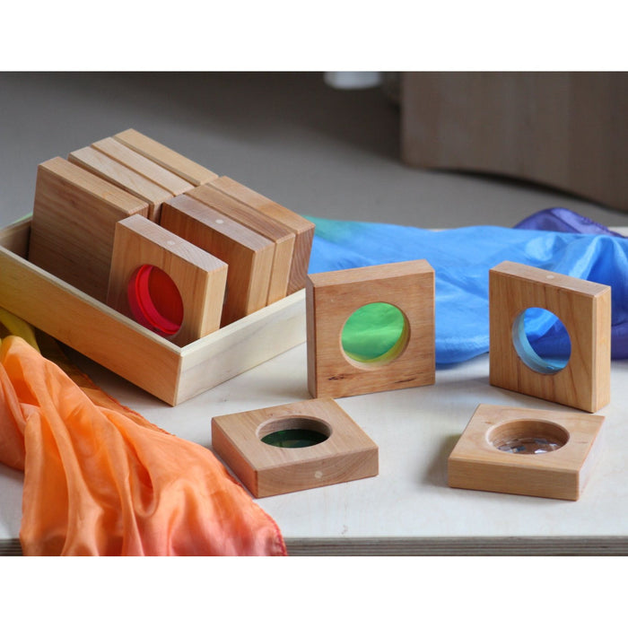 Wooden geometric shape sorting toy on a table with colorful cloths.