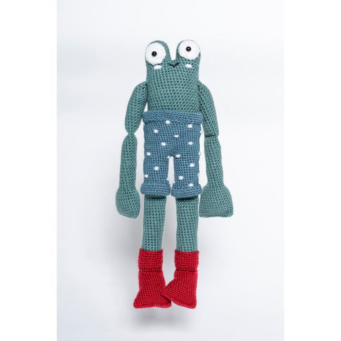 Crocheted toy frog with a polka dot diaper on a white background