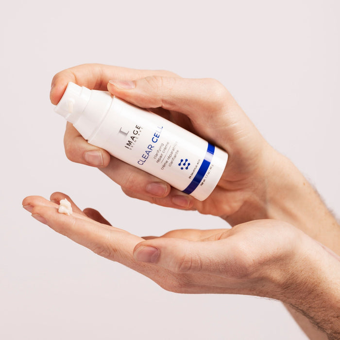 Person dispensing a small amount of CLEAR CELL clarifying repair crème | IMAGE Skincare onto their hand against a light background.