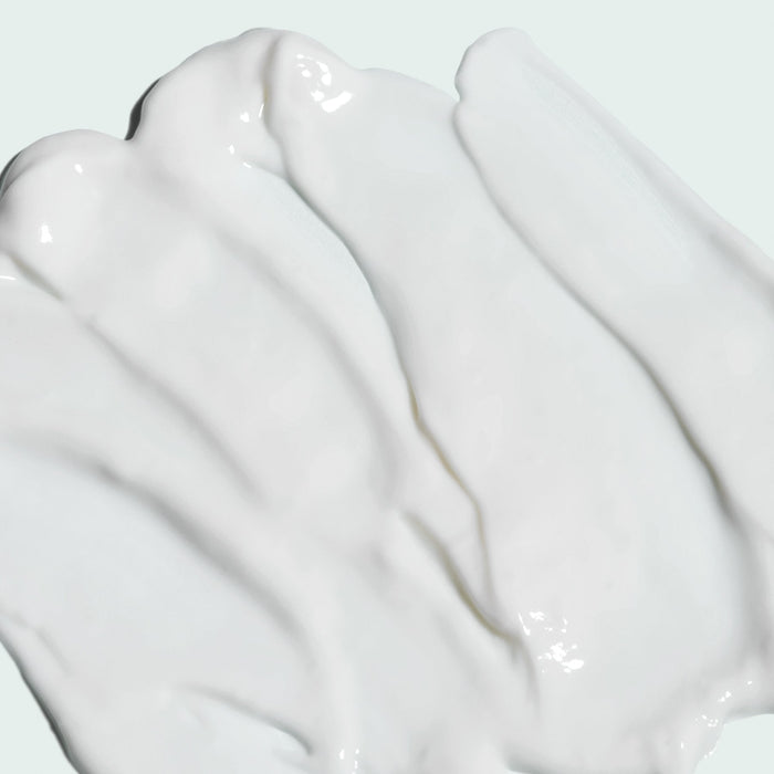 Smooth white creamy texture of ILUMA intense brightening crème | IMAGE Skincare spread on a light background, highlighting its rich skincare formula.
