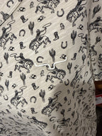 Light tan graphic T-shirt fabric close-up with black cowboy and cactus print