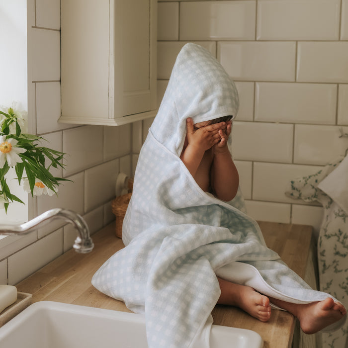 Child in hooded towel in bathroom setting.
