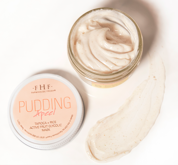 Open jar of Pudding Apeel® Tapioca + Rice Active Fruit Glycolic Mask | FarmHouse Fresh showing creamy beige skincare mask with natural exfoliating texture next to product lid on white surface.