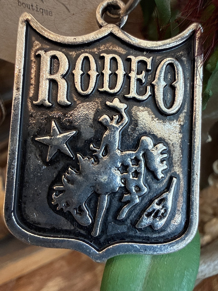 Rodeo shield earring pendant with 'RODEO' text, star and cowboy silhouettes