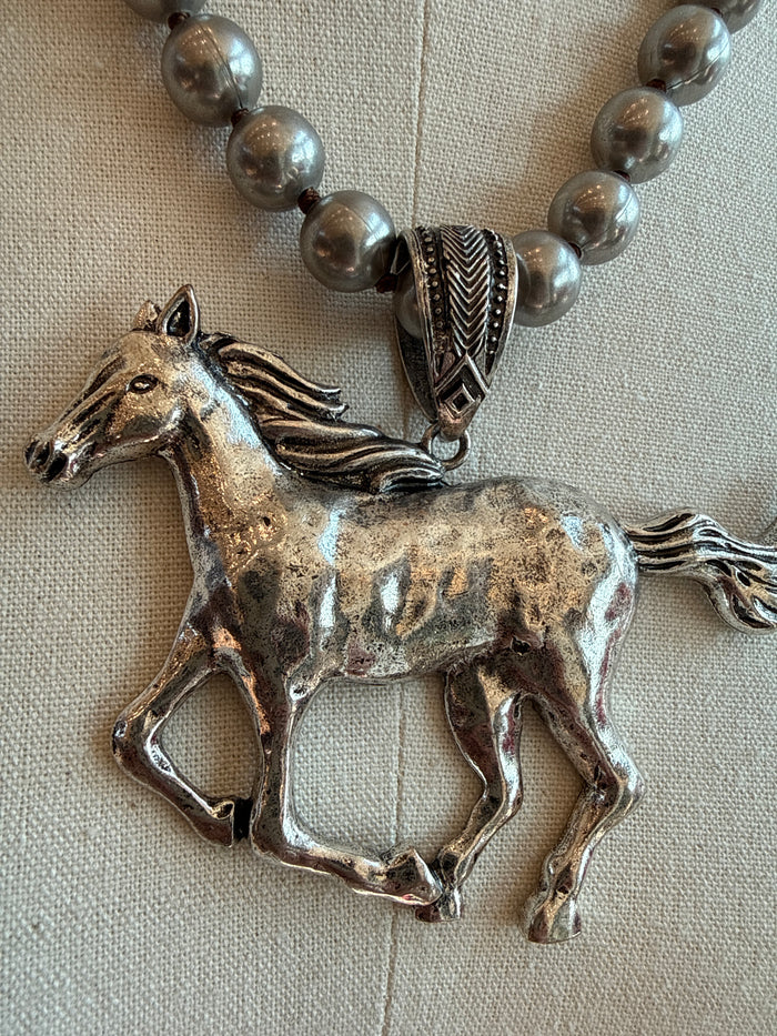 Metallic beaded horse pendant necklace with textured saddle detail on clasp