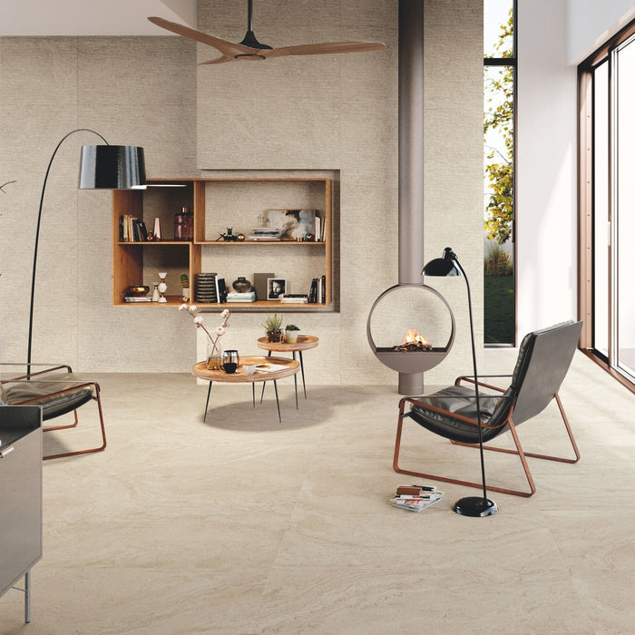 Living space with beige travertine effect wall and floor tiles, round coffee table and leather armchairs.